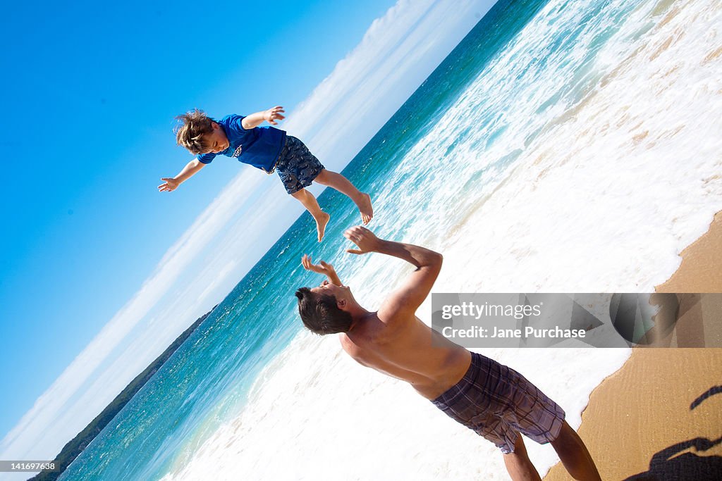 Dad throwing his son in mid air at beach