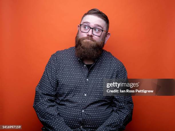 bearded man on orange background making funny faces - wally stock pictures, royalty-free photos & images