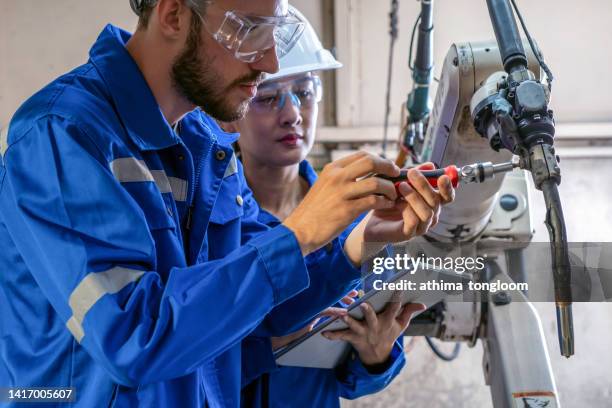 software engineer repairing the robotic arm in a factory. - biomedical engineering photos et images de collection