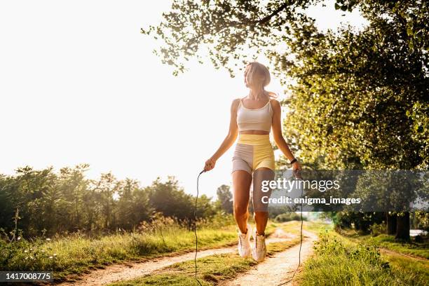 fit young woman with jump rope in a park - spring training stockfoto's en -beelden