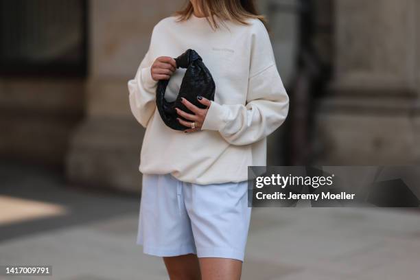 Elise Seitz seen wearing white sunglasses from Celine, a creme white SohoStudios sweater, a light blue SohoStudios shorts and black leather Bottega...