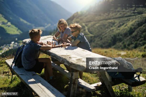 teenage boys playing chess together high in the mountains - travelgame stock pictures, royalty-free photos & images