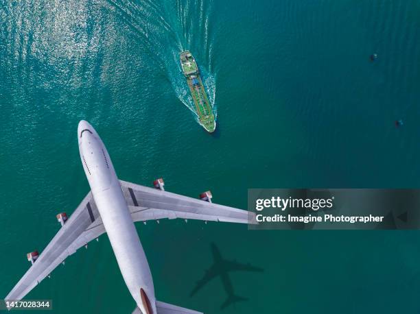 passenger plane flying over green oil tankers are running at high speed and beautiful waves in the sea. - inflamable fotografías e imágenes de stock