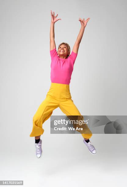 energetic woman jumping - arms raised foto e immagini stock