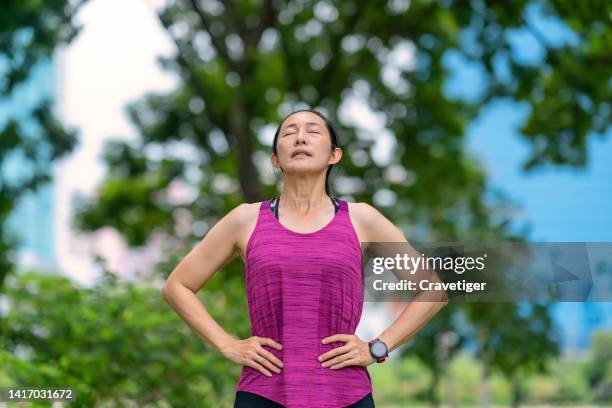 profile of a relaxed asian woman breathing fresh air in a public park after exercise finish. - deep breathing stock pictures, royalty-free photos & images