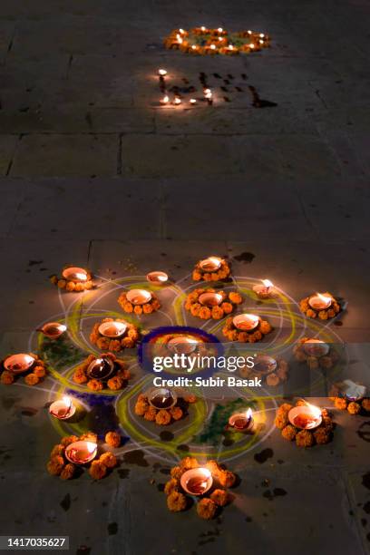 rangoli with diya on the banks of river ganges during diwali,varanasi,uttar pradesh,india. - indian kolam stock-fotos und bilder