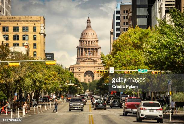pedestres e trânsito descem a avenida congresso pelo edifício do capitólio do estado do texas em austin - federal district - fotografias e filmes do acervo