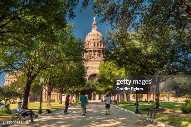 die leute gehen am texas state capitol in austin vorbei - texas state capitol stock-fotos und bilder