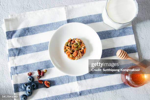 homemade mixed cereal and fruit cookies with a glass of milk and honey bee on white and blue background - breakfast top view stock pictures, royalty-free photos & images