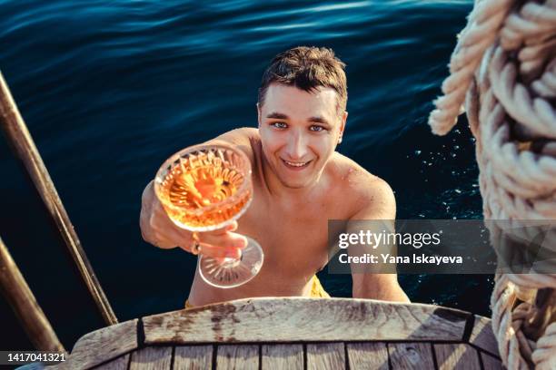 young handsome man is drinking sparkling wine on a yacht - festa di addio al celibato foto e immagini stock