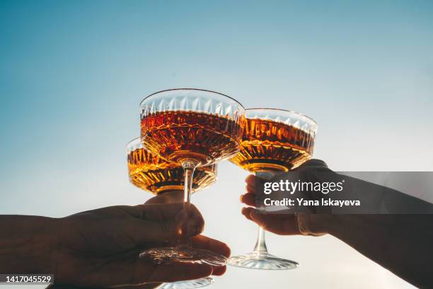 a close-up shot of friends clinking sparkling wine glasses at sunset - cocktail party stock pictures, royalty-free photos & images