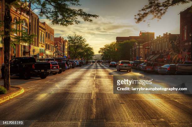 looking into the sunset on main street - small town stockfoto's en -beelden
