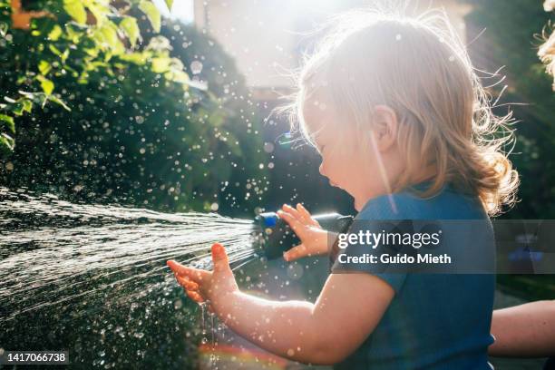 happy toddler girl having fun while splashing with water outdoor. - concepts & topics stock pictures, royalty-free photos & images