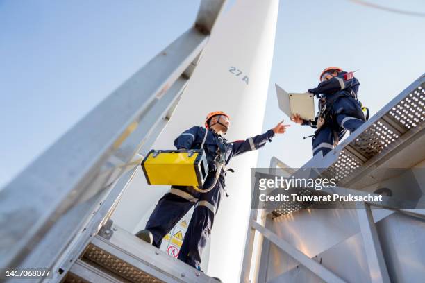 two electric engineer wearing personal protective equipment working at wind turbines farm . - steam turbine stock pictures, royalty-free photos & images
