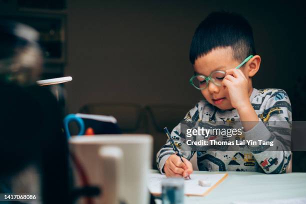5 year old chinese boy doing homework at night - 2 year old child fotografías e imágenes de stock
