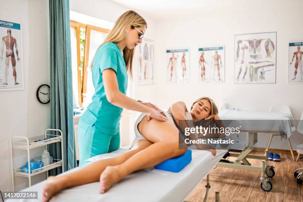 jeune femme chez le physiothérapeute allongée sur son lit - hand on knee photos et images de collection