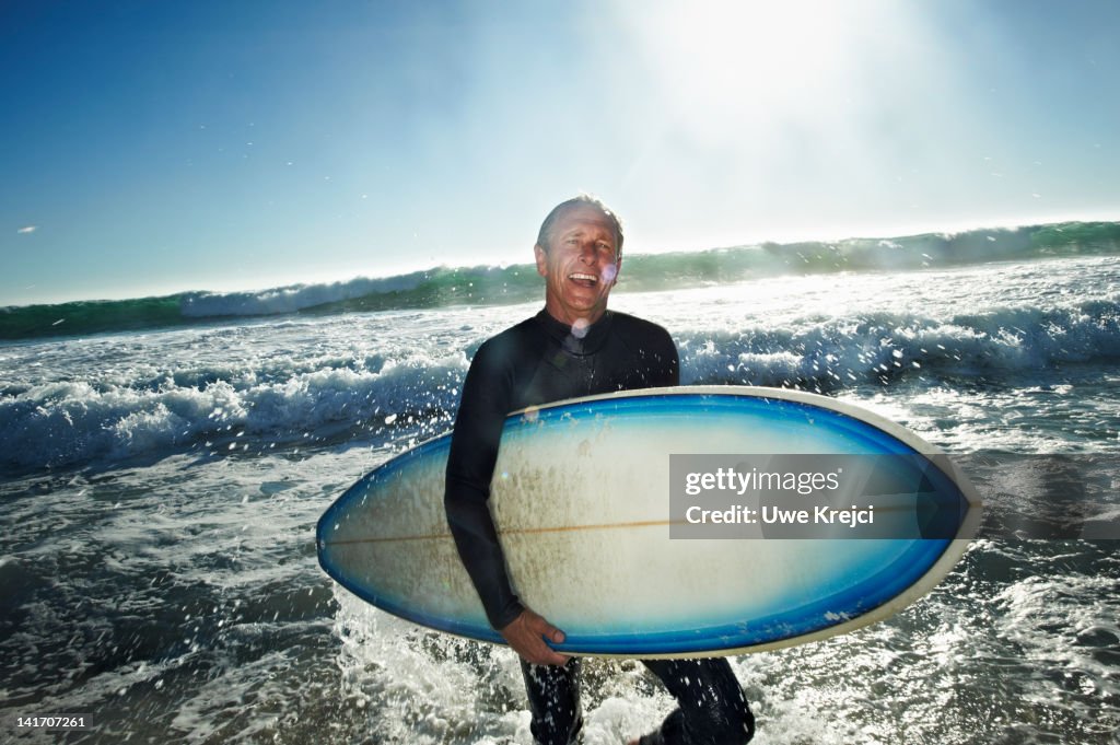 Senior man with surfboard on a beach