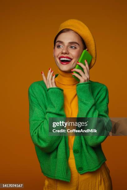 linda mulher emocional com maquiagem brilhante segurando smartphone - vestido verde - fotografias e filmes do acervo