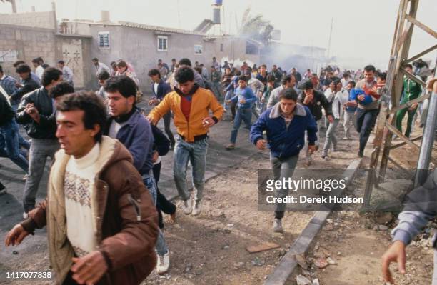 View of people as they run from smoke on an unspecified street during the First Palestinian Intifada, Gaza, Palestine, December 22, 1987.