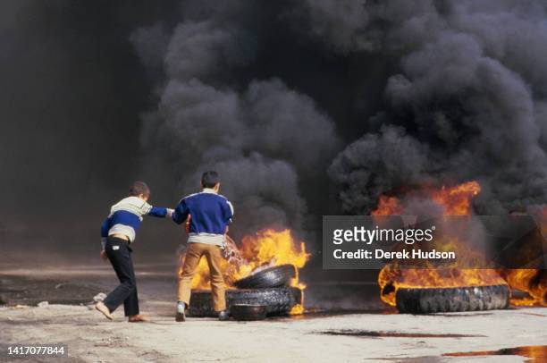 View of two children and a pile of burning tires on an unspecified street induring the First Palestinian Intifada, Gaza, Palestine, December 22, 1987.