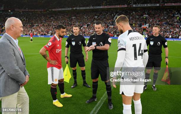 Referee Michael Oliver flips the coin as Bruno Fernandes of Manchester United and Jordan Henderson of Liverpool look on prior to the Premier League...