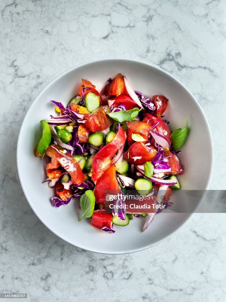 Bowl of fresh tomato salad on white, marble background