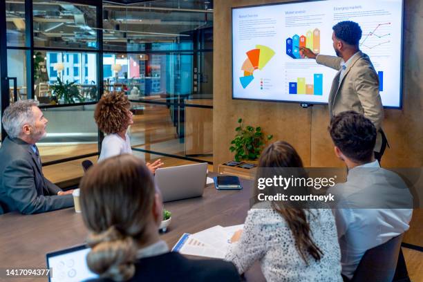 mann, der eine big-data-präsentation auf einem fernseher in einem sitzungssaal hält. - visuelle darstellung stock-fotos und bilder