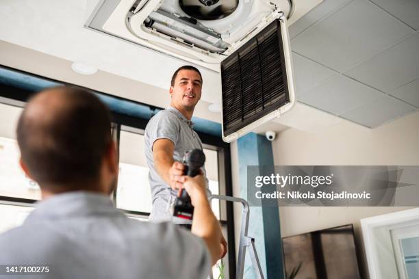 workers checks the air conditioner - installation art stock pictures, royalty-free photos & images