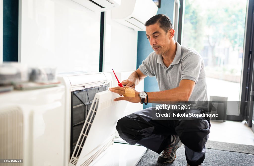 Repairman changing filter on air conditioner