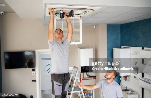 workers install air conditioning workers - ac repair stockfoto's en -beelden