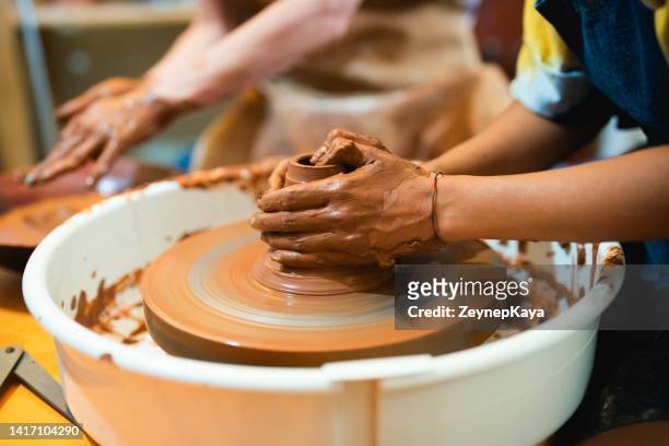 two women shaping the clay on pottery wheel - moulding a shape stock pictures, royalty-free photos & images