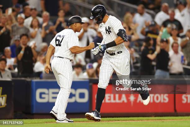 Aaron Judge high-fives third base coach Luis Rojas of the New York Yankees after hitting a home run during the third inning against the New York Mets...