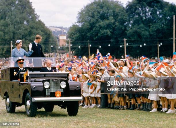 Queen Elizabeth II and Prince Philip waving to a crowd of children in Bathurst, New South Wales, Australia, during their royal tour, February 1954.