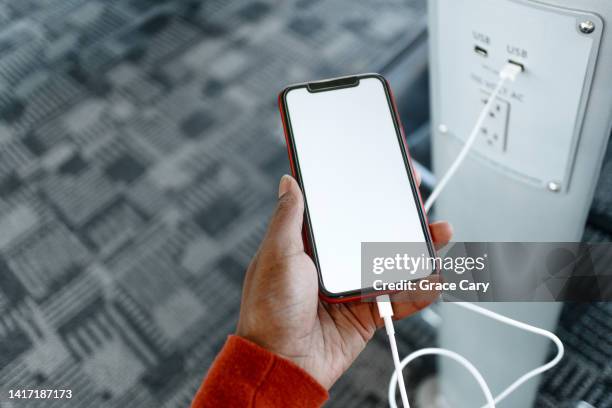 woman charges her smart phone at airport - recharging stock pictures, royalty-free photos & images