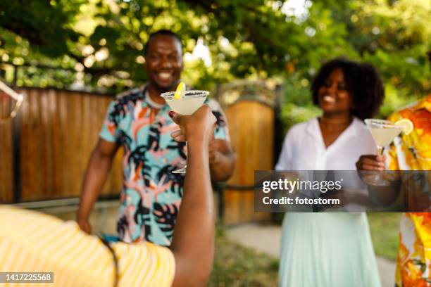 young woman proposing a toast with a glass of margarita cocktail - summer cocktails garden party drinks stockfoto's en -beelden