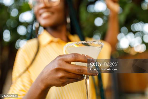 close up shot of cheerful young woman enjoying a margarita cocktail - afro friends home stock pictures, royalty-free photos & images