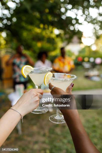 girlfriends making celebratory toast with margarita cocktails - summer cocktails garden party drinks stockfoto's en -beelden