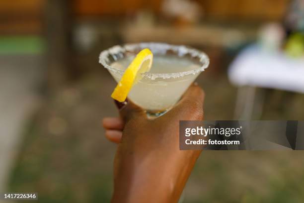 young woman holding a martini glass with delicious margarita cocktail - summer cocktails garden party drinks stockfoto's en -beelden