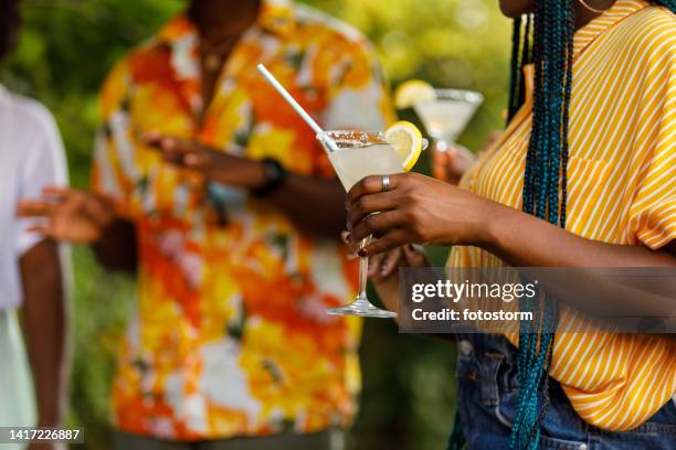 young woman holding a martini glass with margarita cocktail she is enjoying during a garden party - summer cocktails garden party drinks bildbanksfoton och bilder