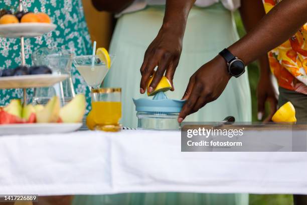 man squeezing a lemon and making lemonade for friends during a garden party - cocktail party at home stock pictures, royalty-free photos & images