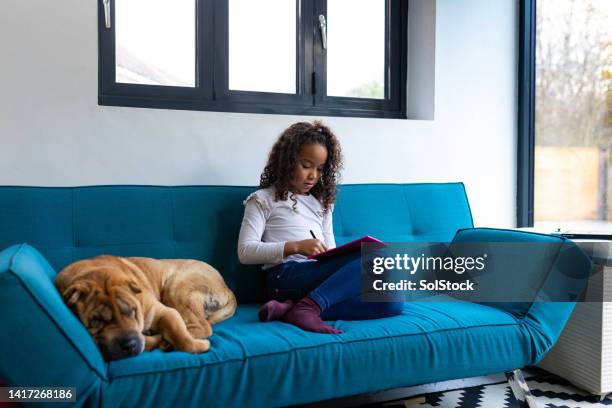 young child taking time to herself - girl on couch with dog stock pictures, royalty-free photos & images