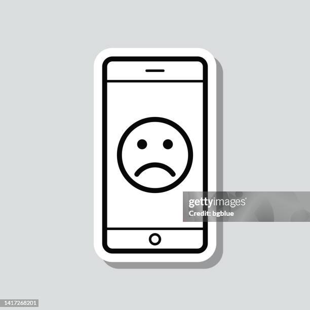 smartphone with sad emoji. icon sticker on gray background - disappointing phone stock illustrations