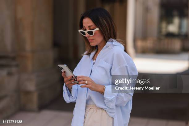 Elise Seitz seen wearing white Celine sunglasses, a light blue SohoStudios shirt, a creme beige shorts from SohoStudios, on August 16, 2022 in...