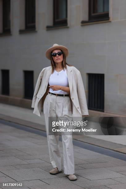 Elise Seitz seen wearing a beige hat, black sunglasses, a white tank top, gold pearl necklace, a beige SohoStudios oversize blazer, black leather...