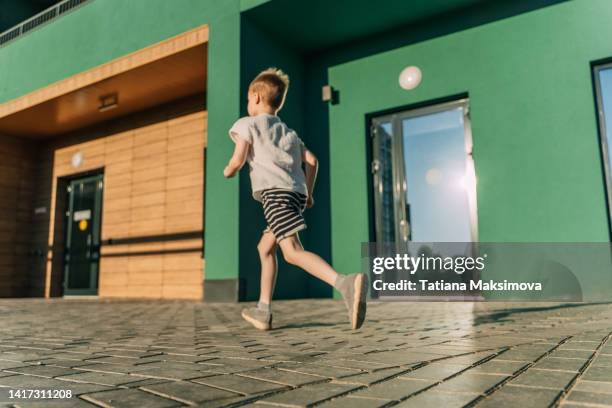 little boy have a fun on green wall background in sunny summer day. - emerald city stock pictures, royalty-free photos & images