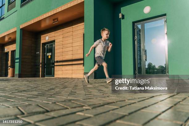 little boy have a fun on green wall background in sunny summer day. - emerald city stock pictures, royalty-free photos & images