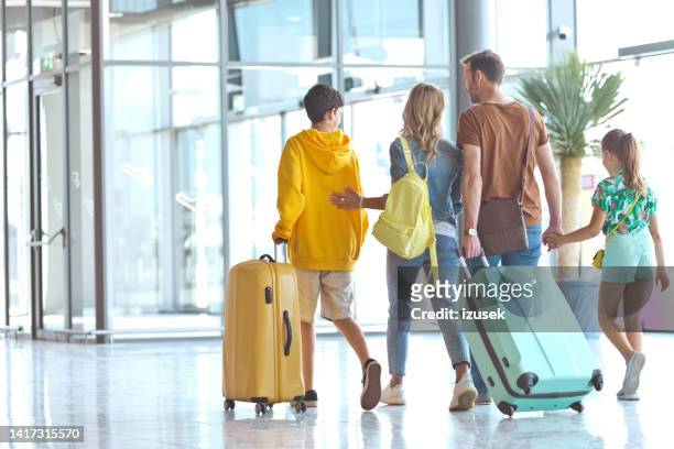 familie mit gepäck, das den flughafen verlässt - airport family stock-fotos und bilder