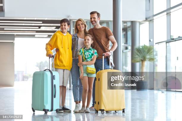 happy family standing at airport - rolling luggage stock pictures, royalty-free photos & images