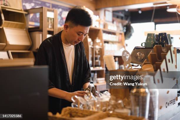 a male barista cleans a cup, ready to make coffee - chinese waiter stock pictures, royalty-free photos & images