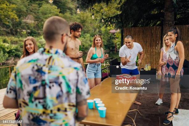 a small group of best friends have crazy fun playing beer pong at the pool - beer pong stock pictures, royalty-free photos & images